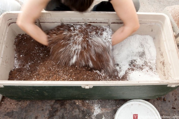 Mixing potting mix by hand in the greenhouse, photographed by Kyo Morishima