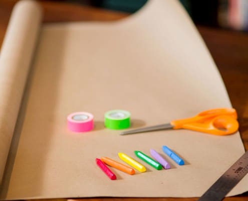 Crayons and kraft paper about to be used as table decor at a casual family dinner party, photographed by Kyo Morishima