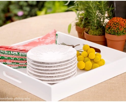 Burlap tablecloth with white plates, red and green napkins, and yellow flowers, photographed by Kyo Morishima