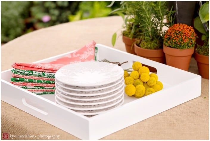 Burlap tablecloth with white plates, red and green napkins, and yellow flowers, photographed by Kyo Morishima