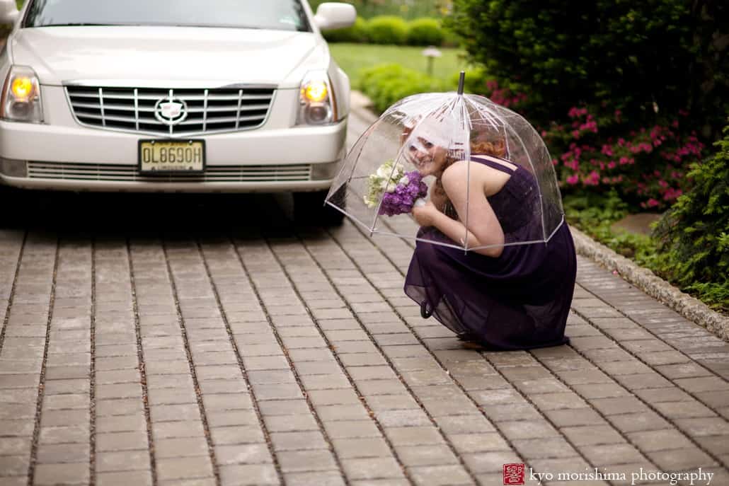 Bridesmaid hides under umbrella during rainy photo session at Van Vleck Gardens, photographed by Montclair wedding photographer Kyo Morishima