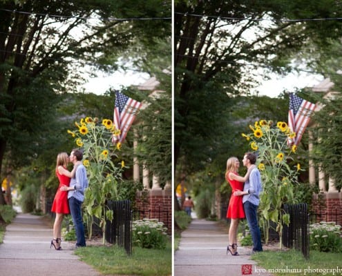 Woman in a red dress kisses her fiancé next to sunflowers and an American flag, photographed by Lambertville engagement photographer Kyo Morishima