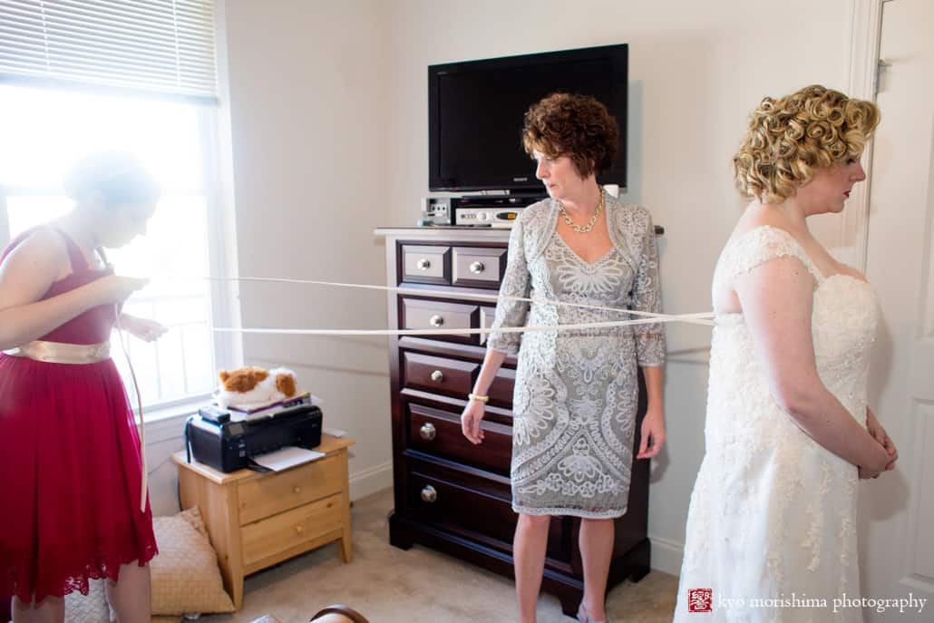Mother of the bride and maid of honor help bride put on her dress at Westin Forrestal Village, photographed by Princeton wedding photographer Kyo Morishima