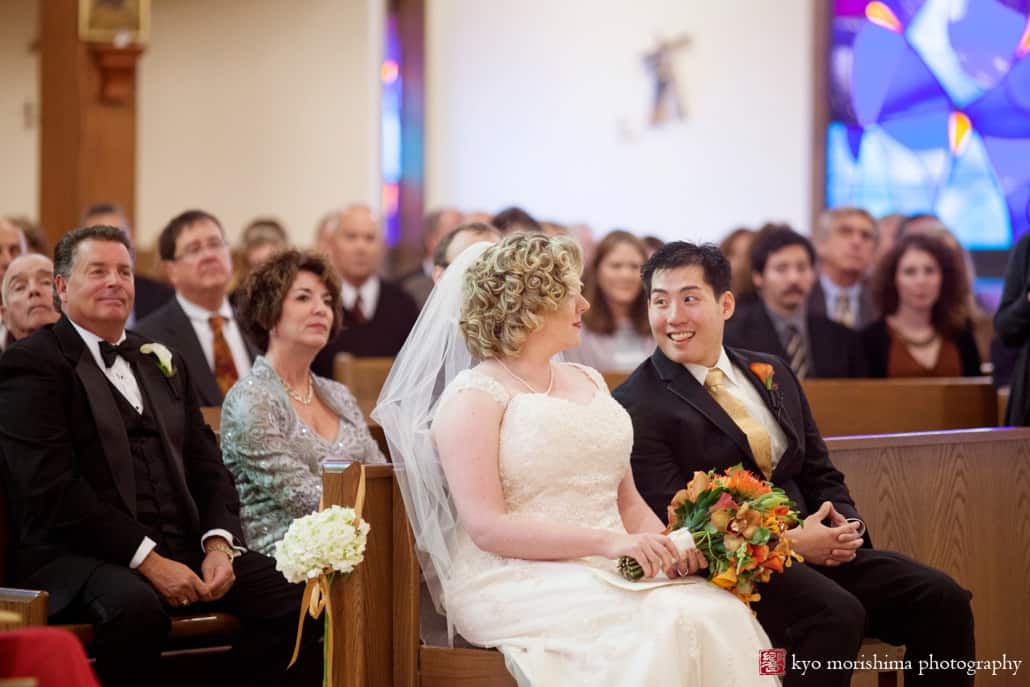 Groom glances over and smiles at bride during Queenship of Mary Church wedding ceremony, photographed by Kyo Morishima