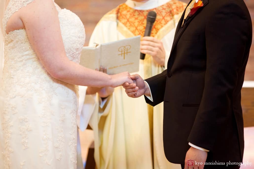Groom holds bride's hand during Queenship of Mary Church wedding ceremony in Plainsboro, photographed by Kyo Morishima