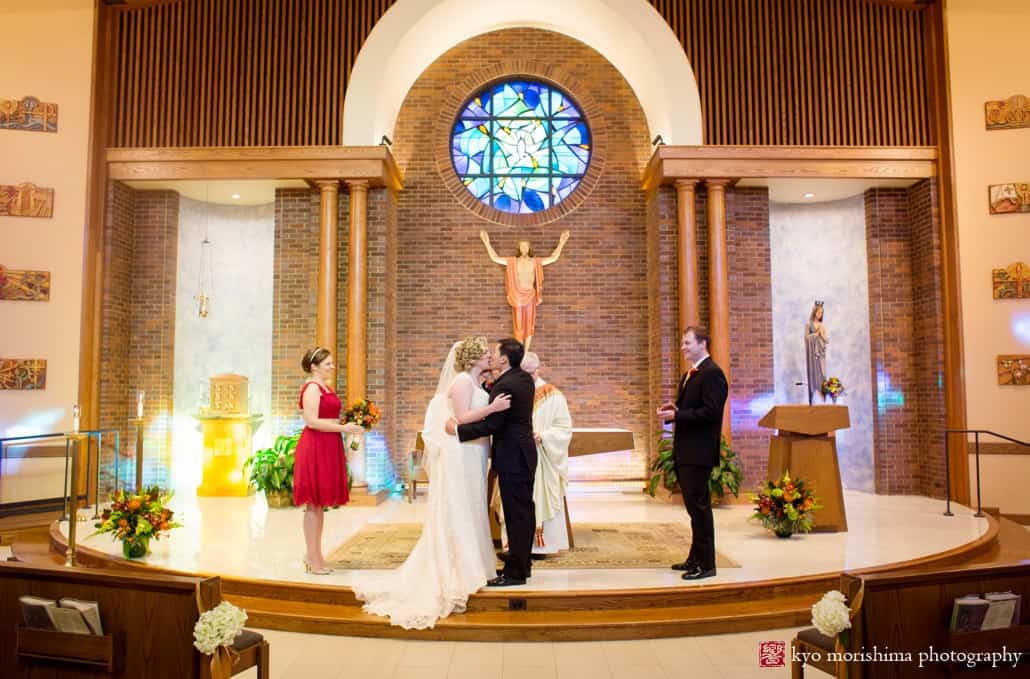 Bride and groom embrace at altar in Queenship of Mary Church, photographed by Plainsboro wedding photographer Kyo Morishima