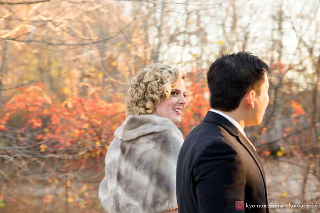 Bride wearing grey fur stole glances over at groom during walk at New Jersey Audubon Plainsboro Preserve, photographed by Kyo Morishima