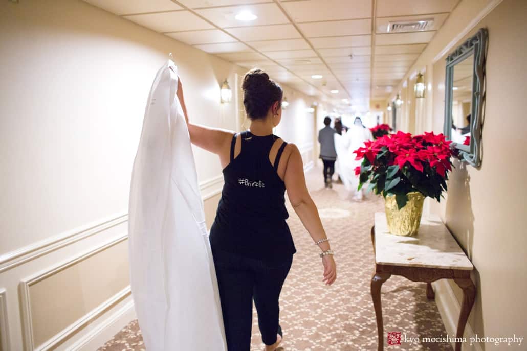 Maid of honor carries wedding dress to bride's room at Olde Mill Inn, photographed by NJ wedding photographer Kyo Morishima