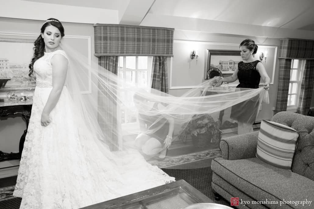 Bridesmaid lifts bride's veil as she gets ready for her Olde Mill Inn wedding, photographed by Basking Ridge wedding photographer Kyo Morishima