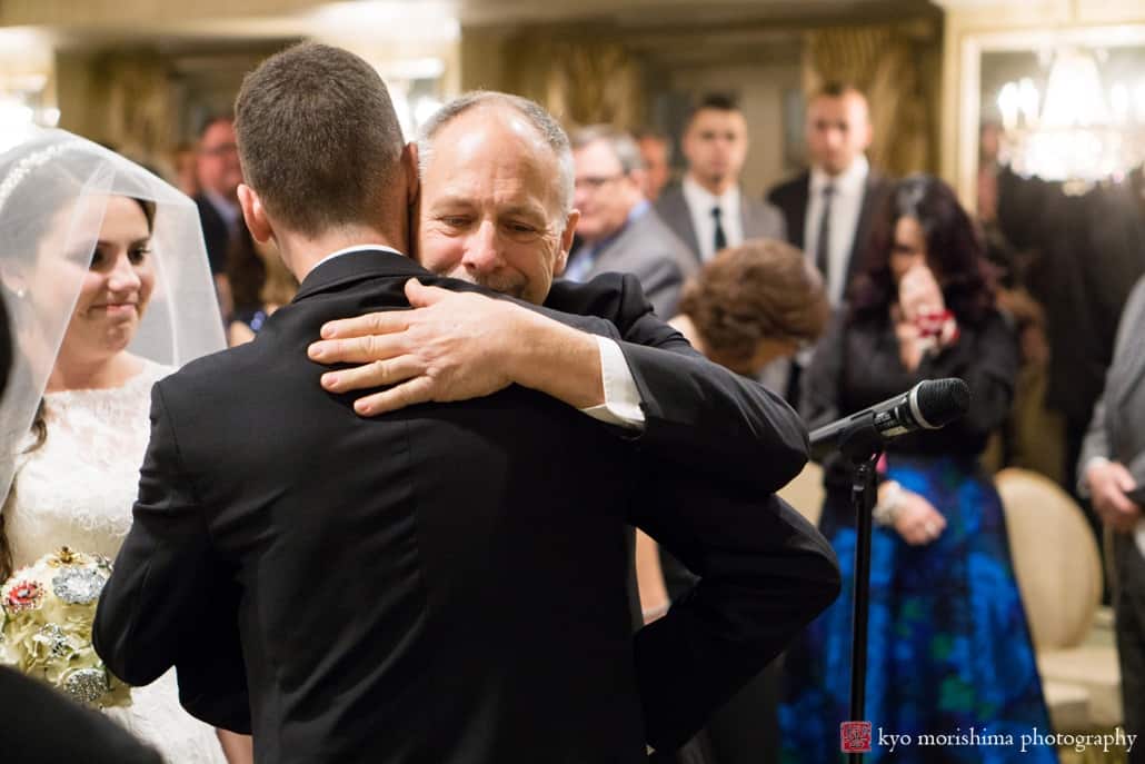 Father of the bride hugs groom during Olde Mill Inn wedding ceremony, photographed by Kyo Morishima