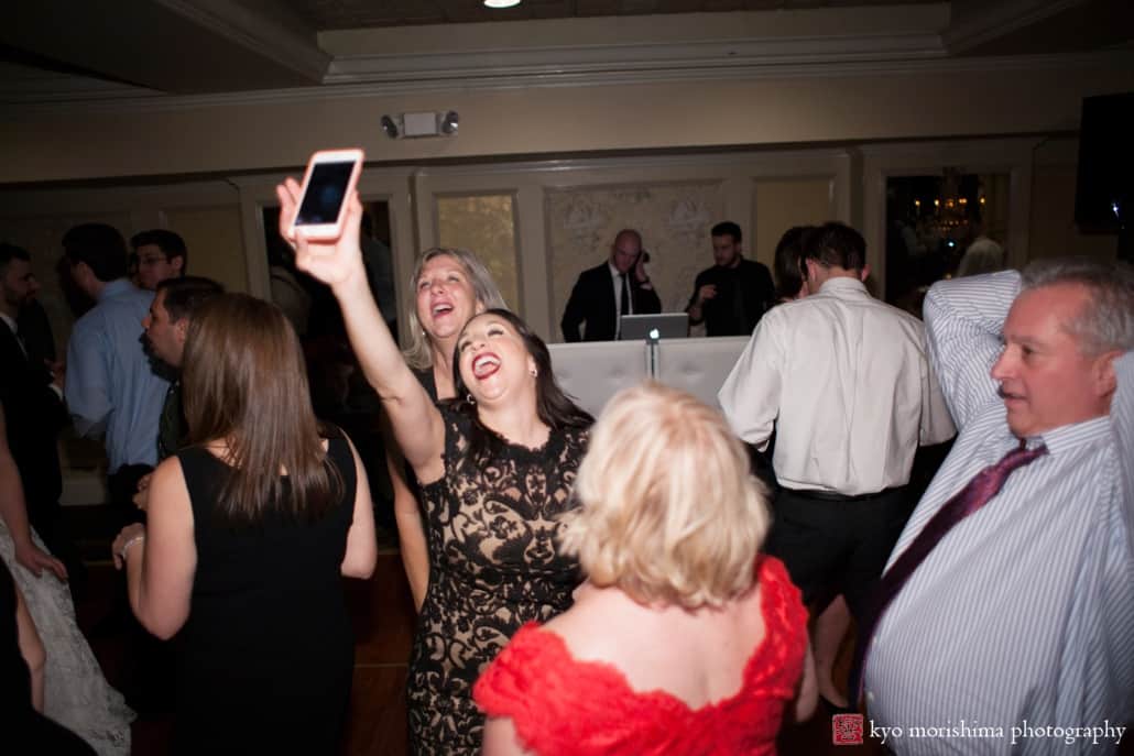 Wedding guest enthusiastically takes a selfie on the dance floor, photographed by Kyo Morishima