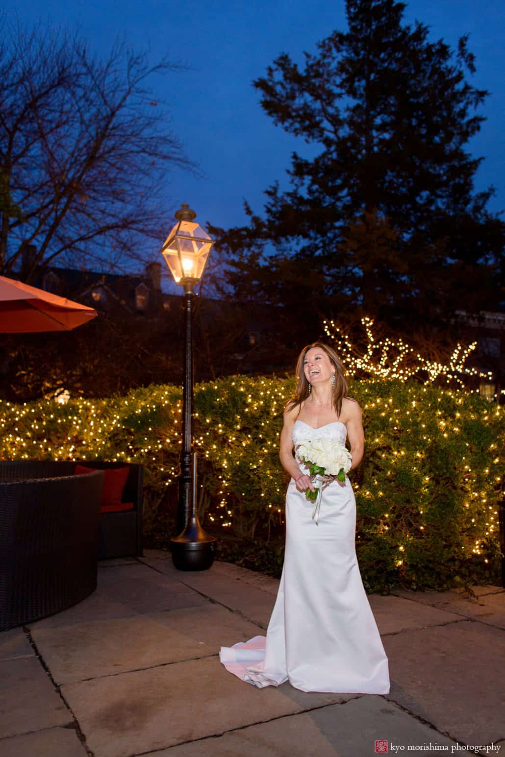 Bride laughs as she poses on Nassau Inn patio during a March evening wedding, photographed by Kyo Morishima