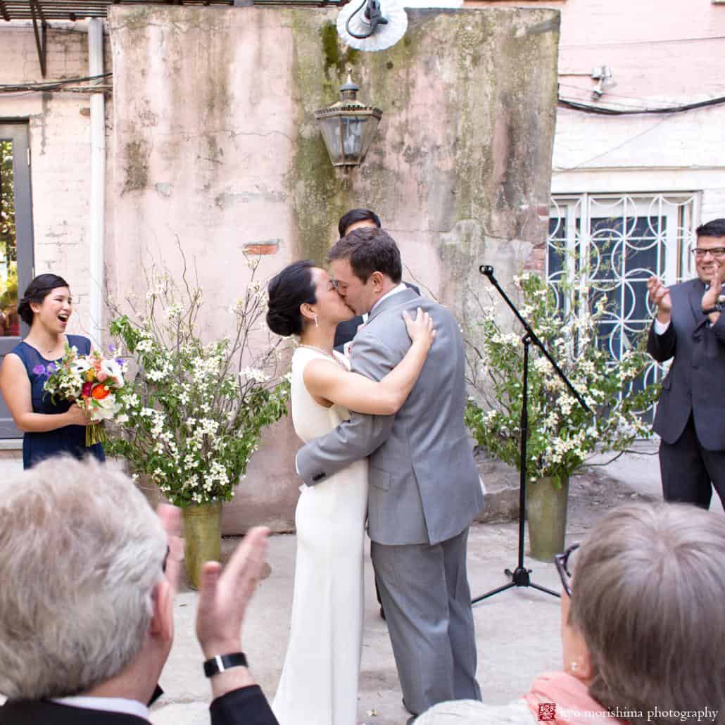 Bride and groom kiss at the end of Invisible Dog Art Center courtyard wedding ceremony coordinated by Polka Dot Events, photographed by Kyo Morishima