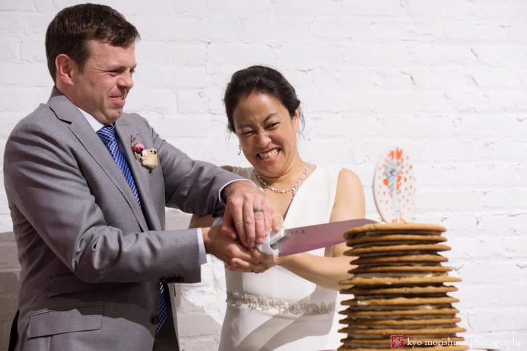 Bride and groom attach chocolate chip cookie wedding cake at Invisible Dog Art Center wedding, photographed by Kyo Morishima