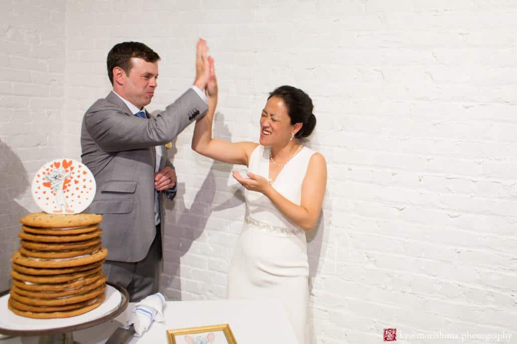 Bride and groom high five after cutting the cake at Invisible Dog Art Center, photographed by Kyo Morishima