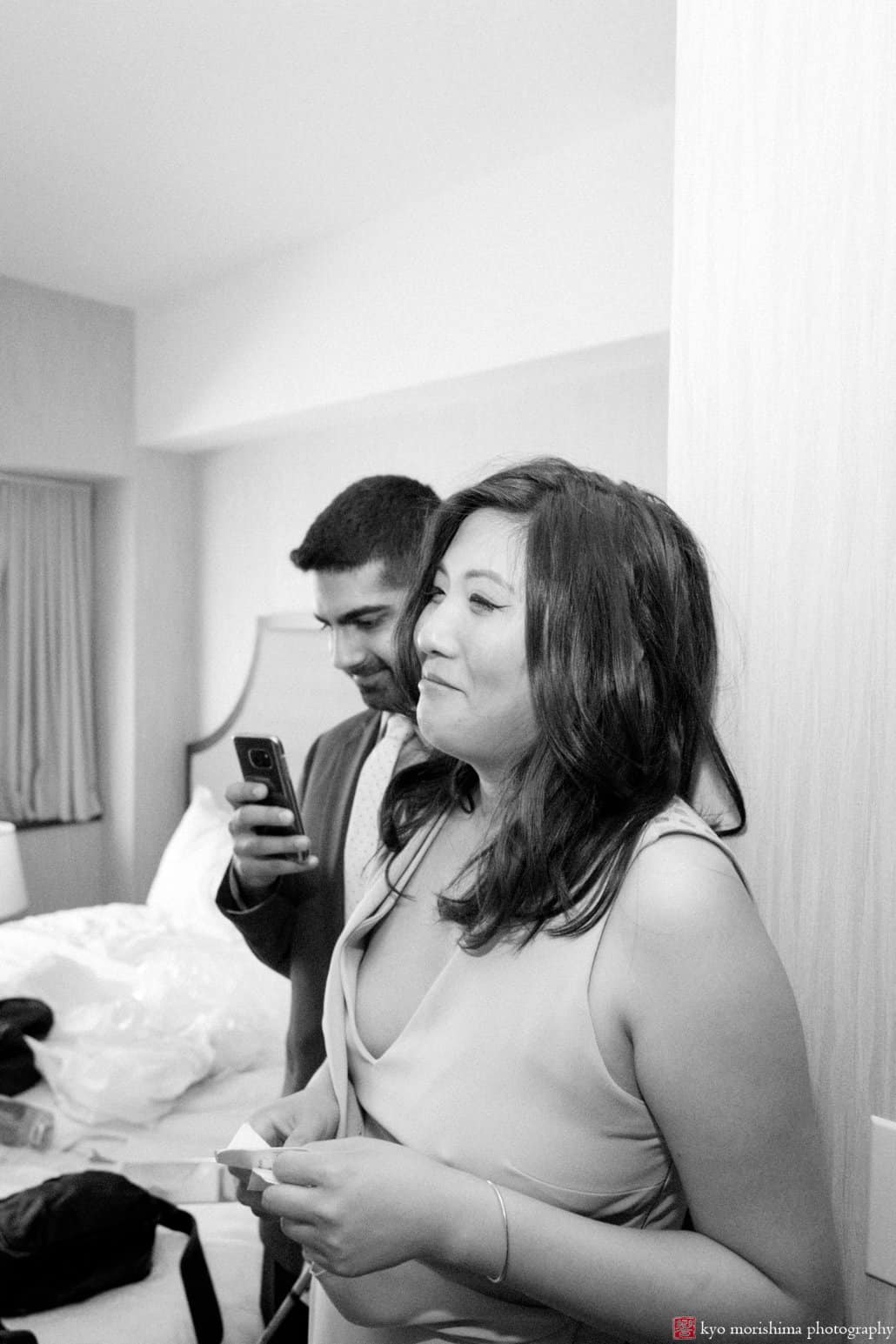 Bridesmaid and friend watch bride getting ready at Lincoln Harbor Sheraton, photographed by Weehawken wedding photographer Kyo Morishima