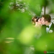 A glimpse of bride and groom kissing through greenery at Jasna Polana, photographed by Princeton wedding photographer Kyo Morishima