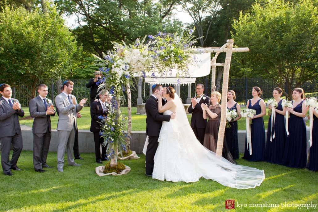 Bride and groom kiss under chuppah by Katherine Toland during Princeton garden wedding ceremony at Jasna Polana, photographed by Kyo Morishima