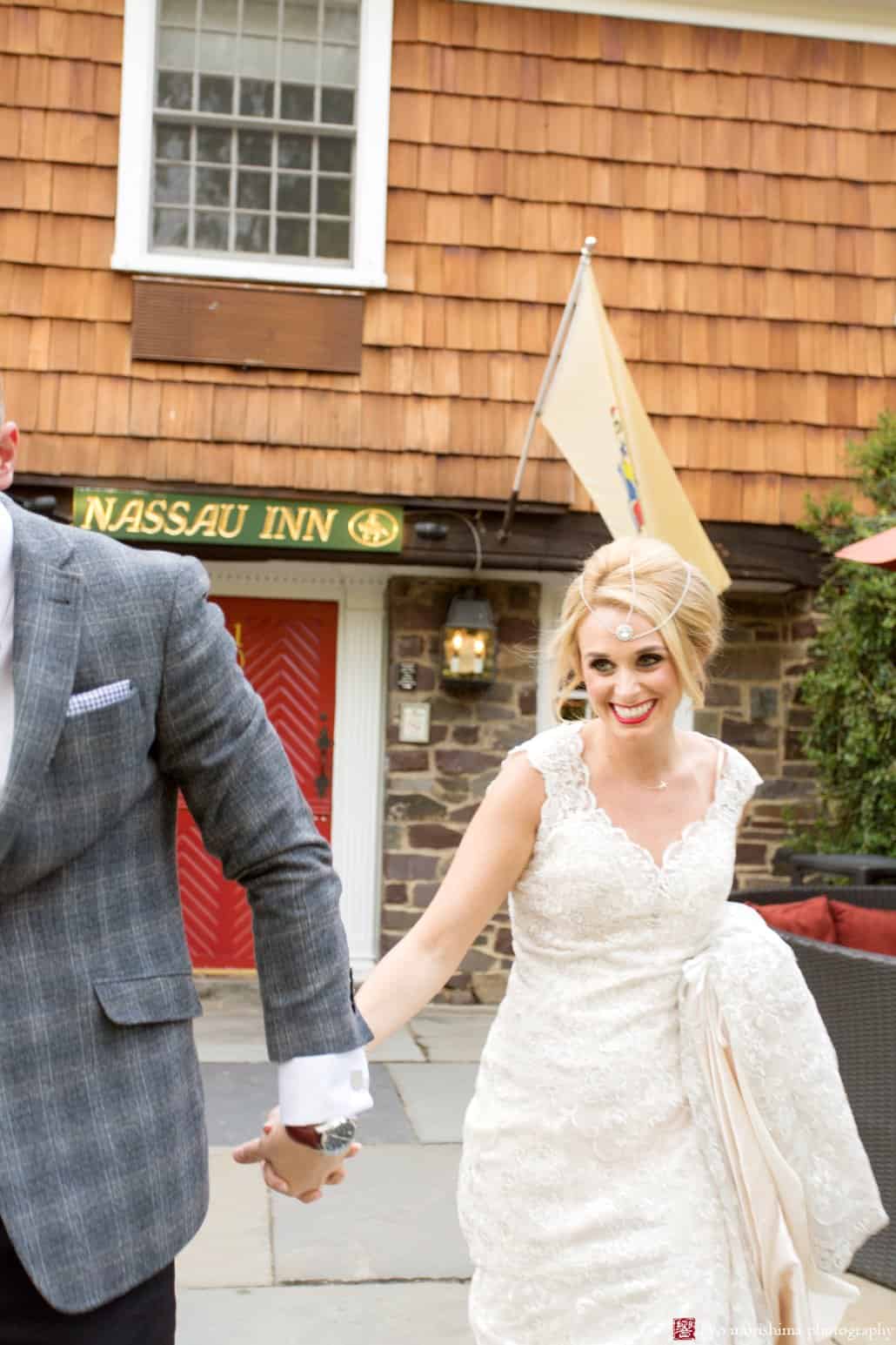 Bride and groom celebrate outside red door of Nasssau Inn in Princeton. Bride wears BHLDN wedding gown. photographed by Kyo Morishima