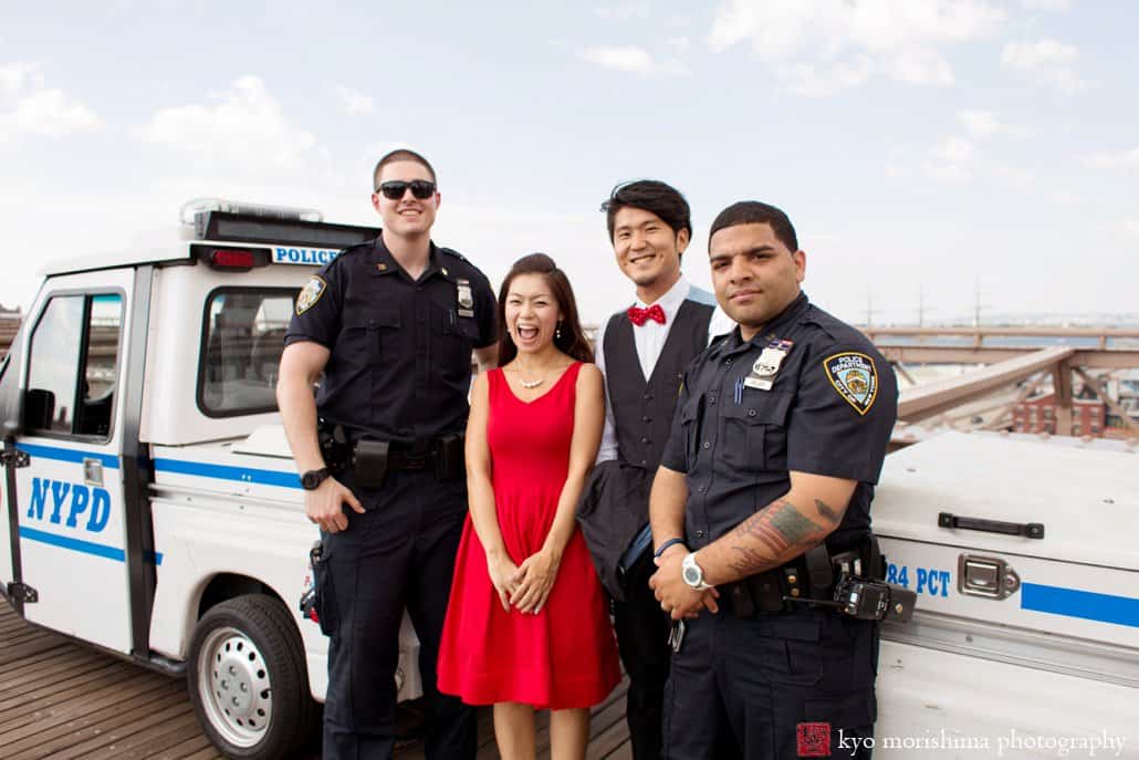 Japanese couple poses with NYPD for engagement photo near Brooklyn Bridge photographed by Kyo Morishima