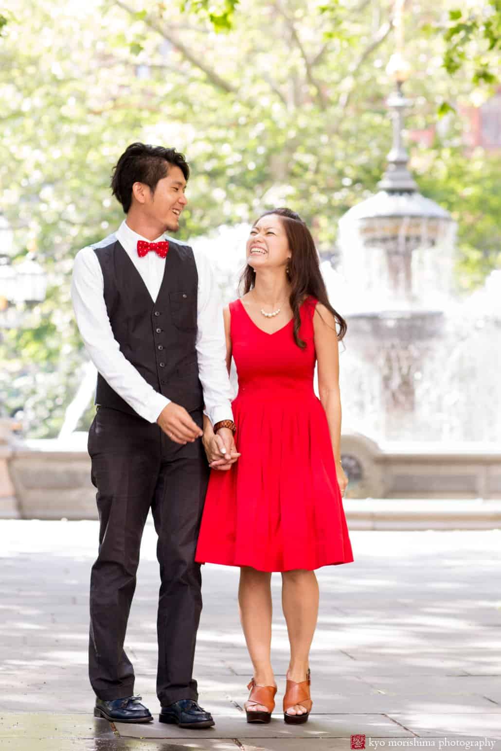 Japanese couple smiles near fountain in downtown NYC; engagement photo photographed by Kyo Morishima