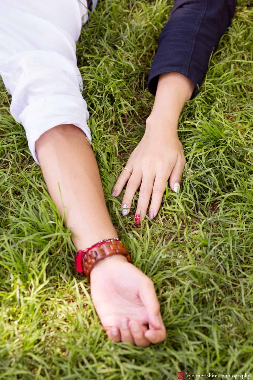 Man and woman's hands outstretched on the grass photographed by Kyo Morishima