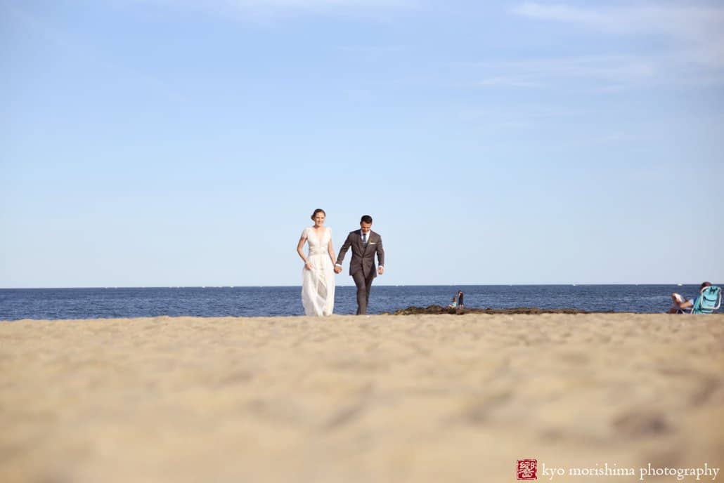 Bride and groom walk across sand during Asbury Park wedding, photographed by Kyo Morishima