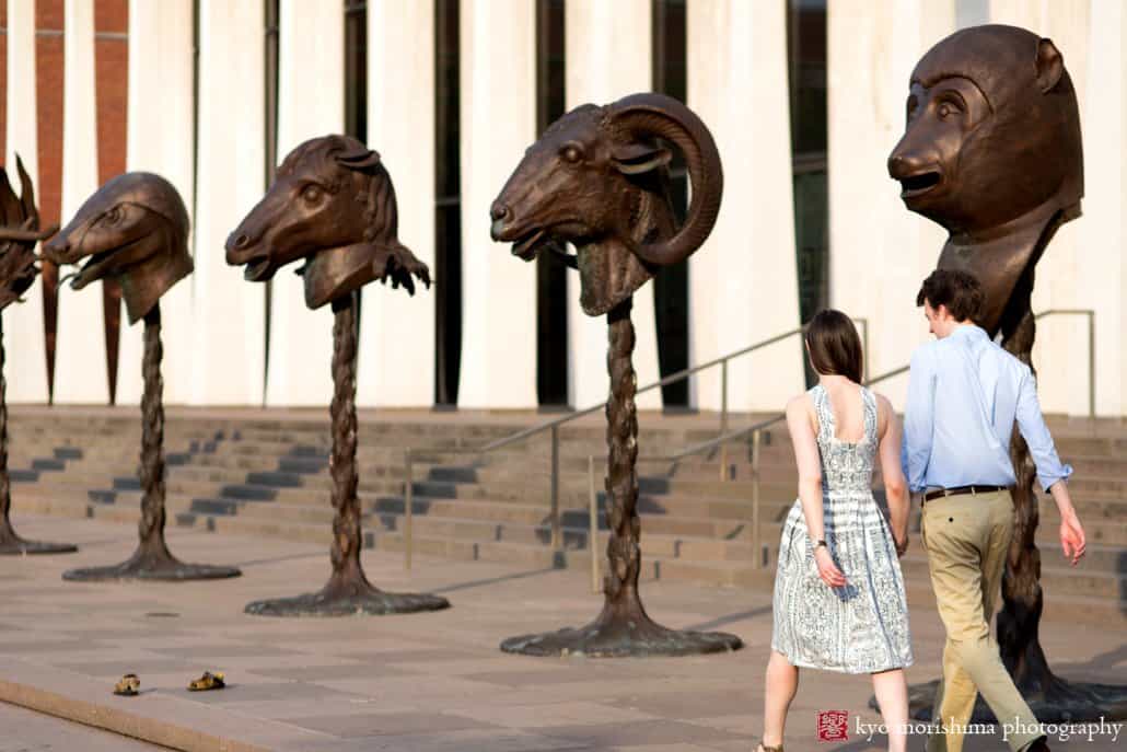 Couple walks alongside zodiac sculptures by Ai Weiwei outside Princeton University Art Museum; engagement photo photographed by Kyo Morishima