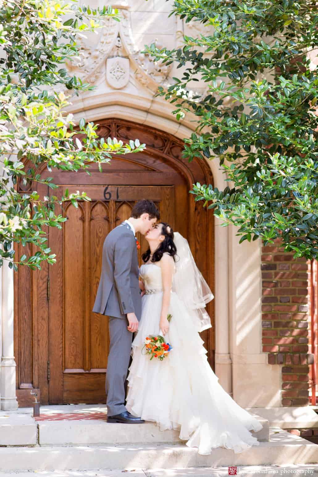 Bride and groom kiss on the stone steps in front of old wooden door during Cap and Gown Club wedding portrait session photographed by Princeton wedding photographer Kyo Morishima
