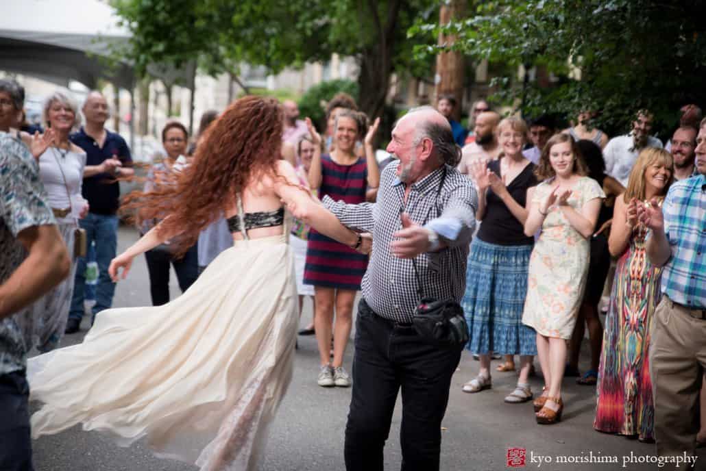 Man with camera around his neck spins around with red-headed bride at West Philadelphia block party wedding photographed by Kyo Morishima