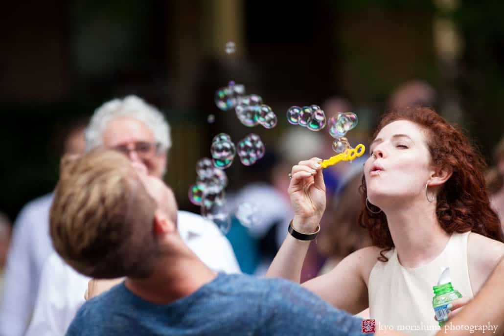 Bride blows bubbles during West Philadelphia block party wedding photographed by Kyo Morishima