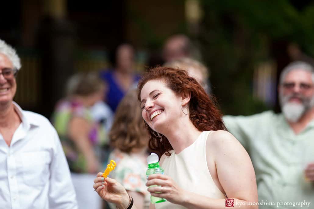 Bride laughs after blowing bubbles during West Philadelphia block party wedding photographed by Kyo Morishima