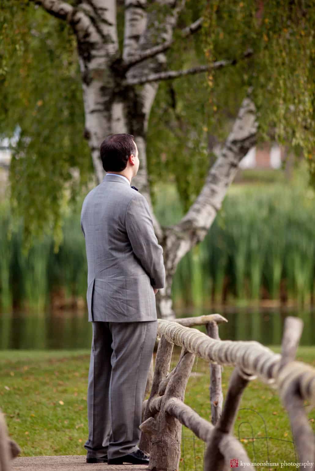 Groom awaits first look next to weeping willow tree, photographed by Perona Farms wedding photographer Kyo Morishima