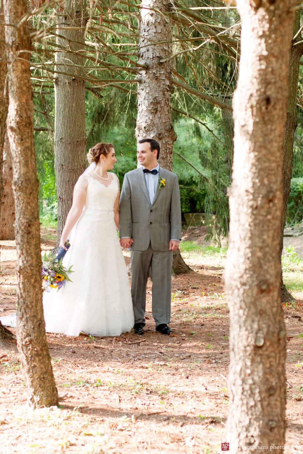 Bride and groom go for a walk through pine grove at Perona Farms photographed by Sussex County wedding photographer Kyo Morishima