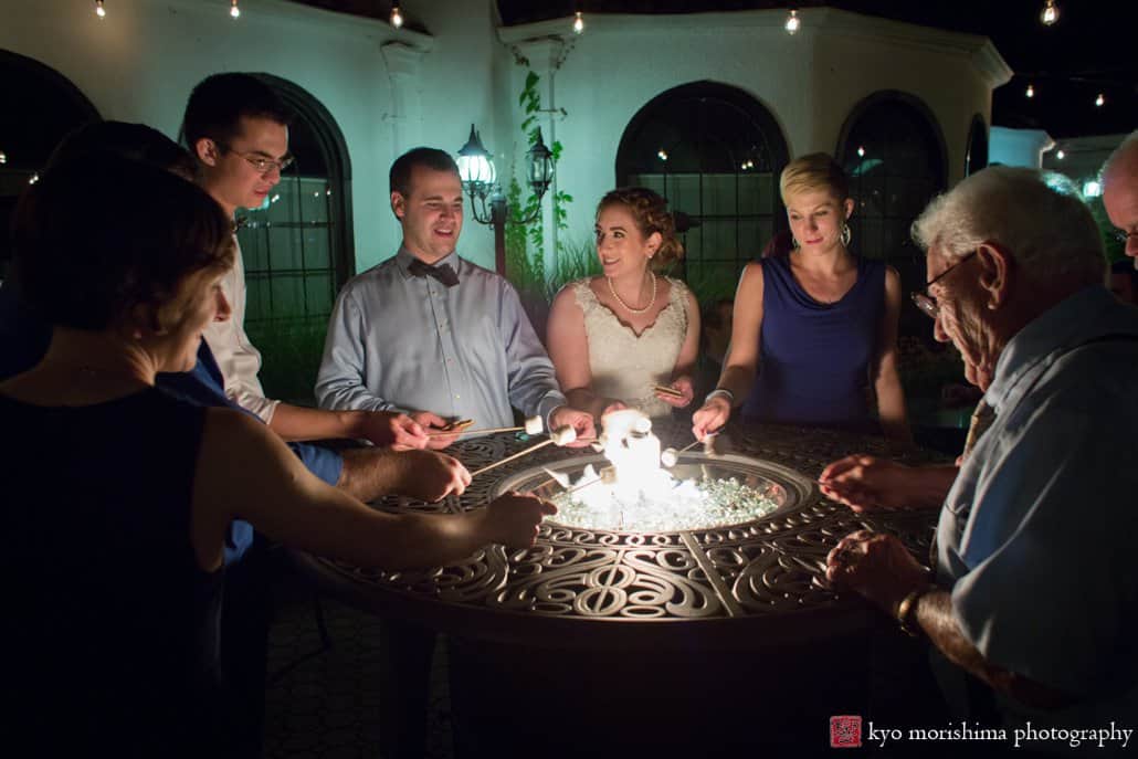 Bride, groom, and guests grill s'mores in the courtyard at Perona Farms wedding, photographed by Kyo Morishima
