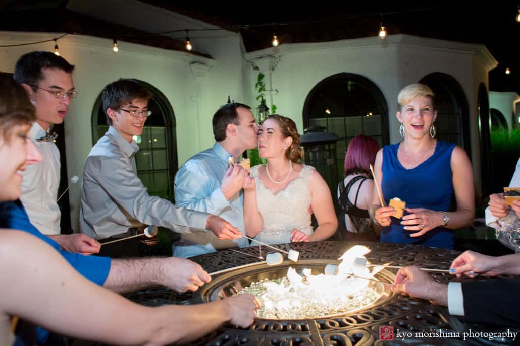 Groom kisses bride in Perona Farms courtyard while they grill s'mores, photographed by NJ documentary wedding photographer Kyo Morishima