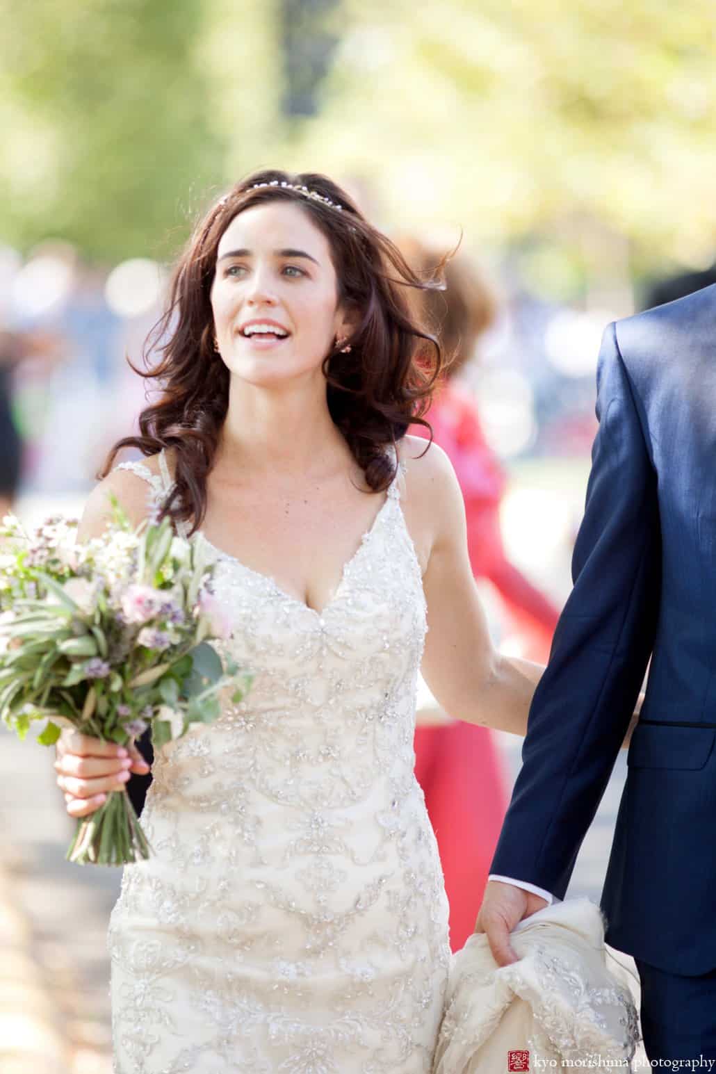 Bride smiles while walking to Governors Island wedding ceremony; dress by Maggie Sottero, photographed by Kyo Morishima