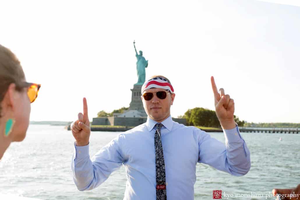 Wedding guest wearing star-spangled bandana poses in front of Statue of Liberty, photographed by Kyo Morishima