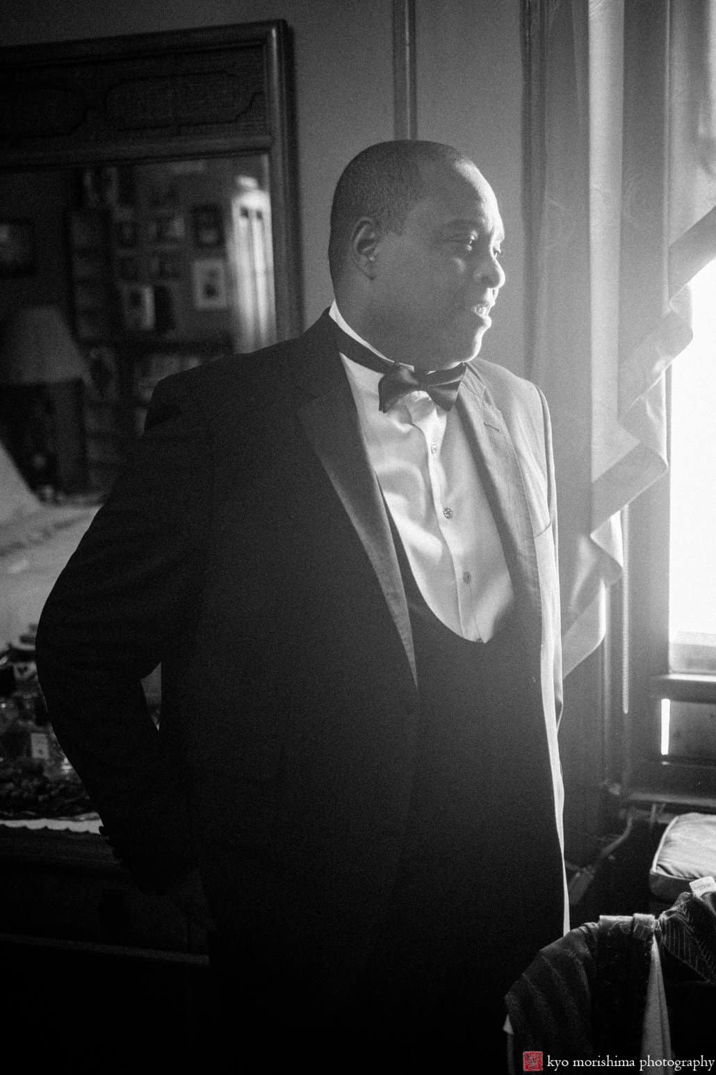 Groom smiles as light pours in the window of Harlem brownstone, photographed by Carlo Cipriani for Kyo Morishima Photography