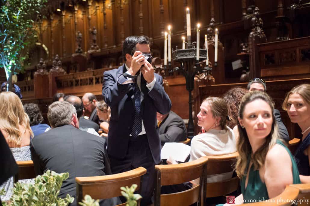 Wedding guest takes a photo as guests arrive for St. John the Divine wedding, photographed by Kyo Morishima