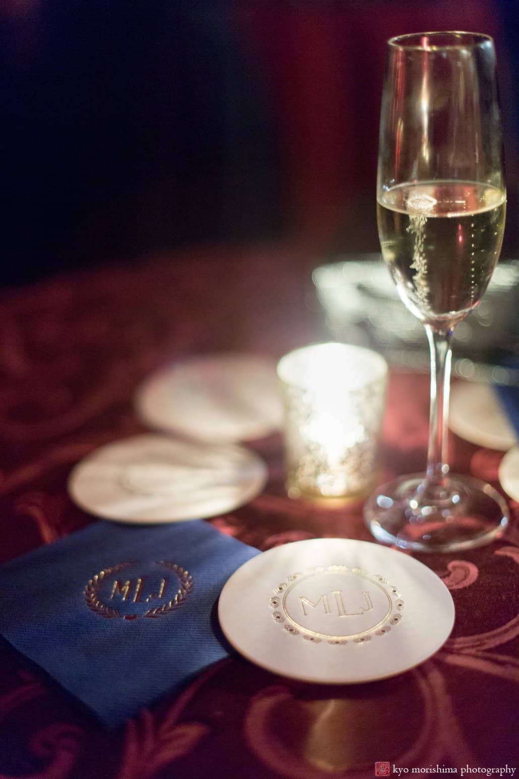 Champagne glass with custom blue, white, and gold monogram coasters at Lotos Club wedding photographed by Kyo Morishima