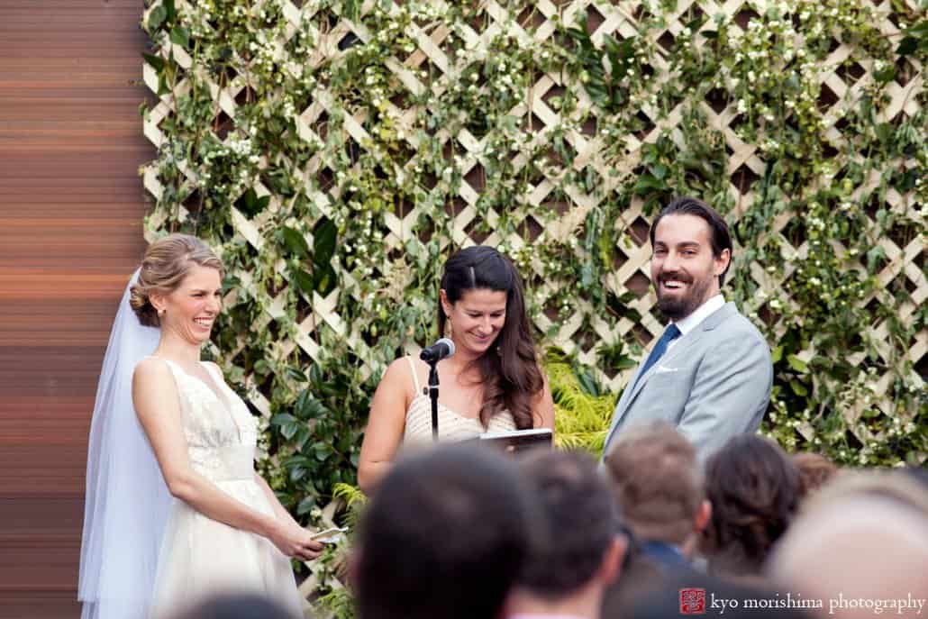 Bride and groom laugh as officiant speaks during Green Building wedding in Brooklyn, photographed by Kyo Morishima