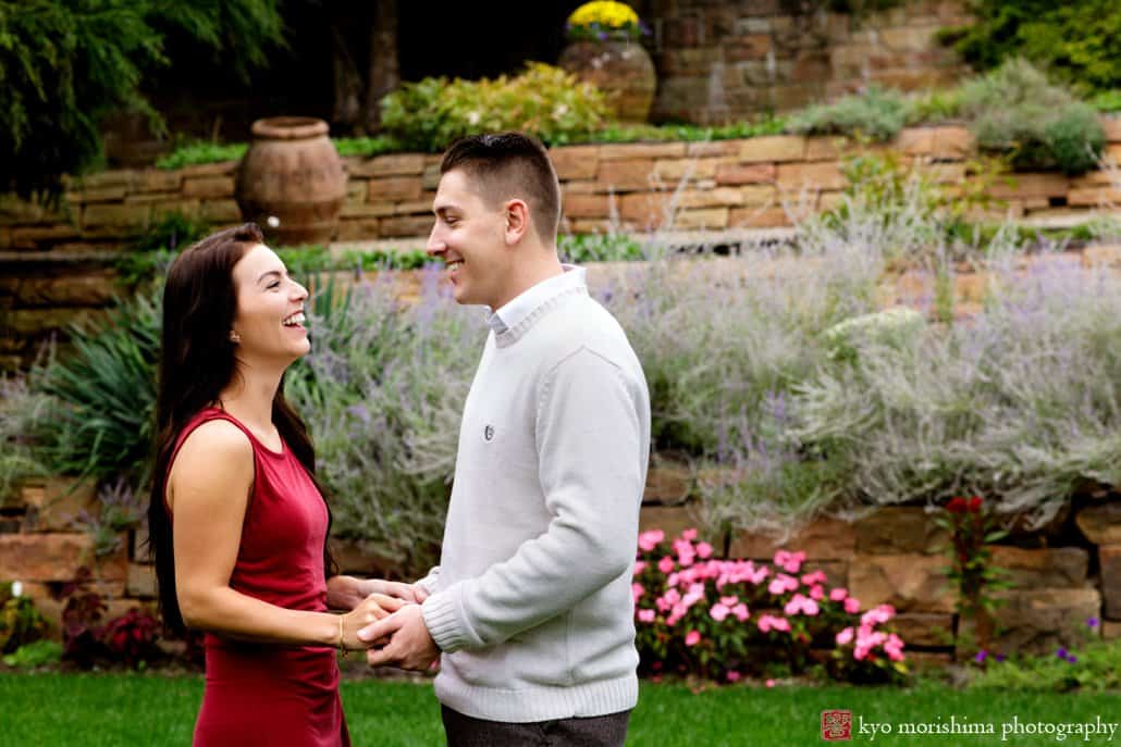 Jasna Polana engagement picture with stone wall and garden in the background