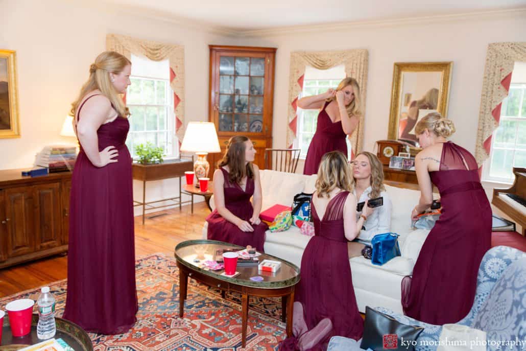 Bride getting ready in the living room surrounded by her bridesmaids wearing maroon Amsale dresses, photographed by Kyo Morishima