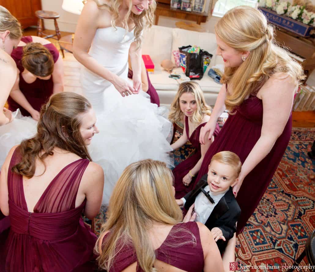 Ringbearer looks up at camera as bride and bridesmaids get ready