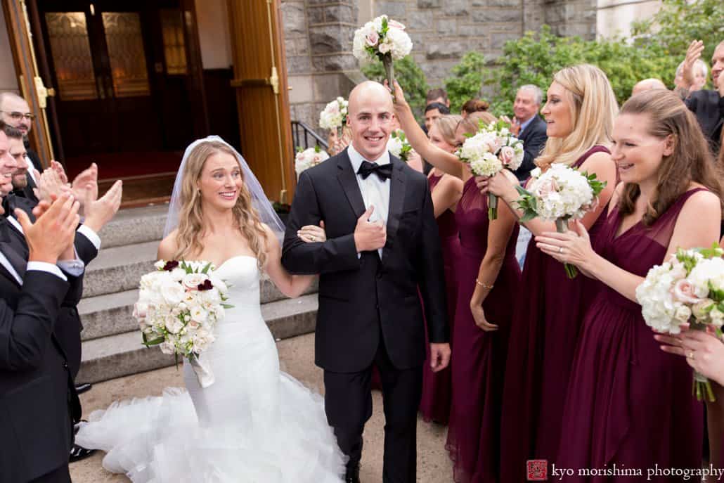 Bride and groom smile happily as bridesmaids cheer their exit from Princeton United Methodist Church wedding ceremony