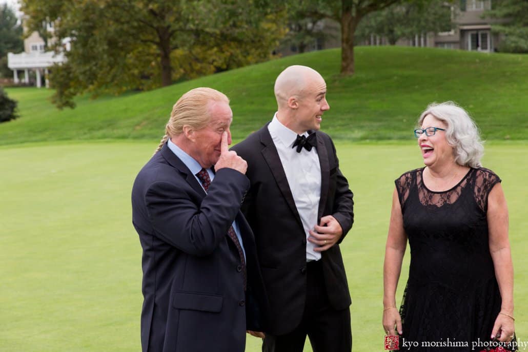 Groom laughs with parents on the golf course at Cherry Valley Country Club wedding