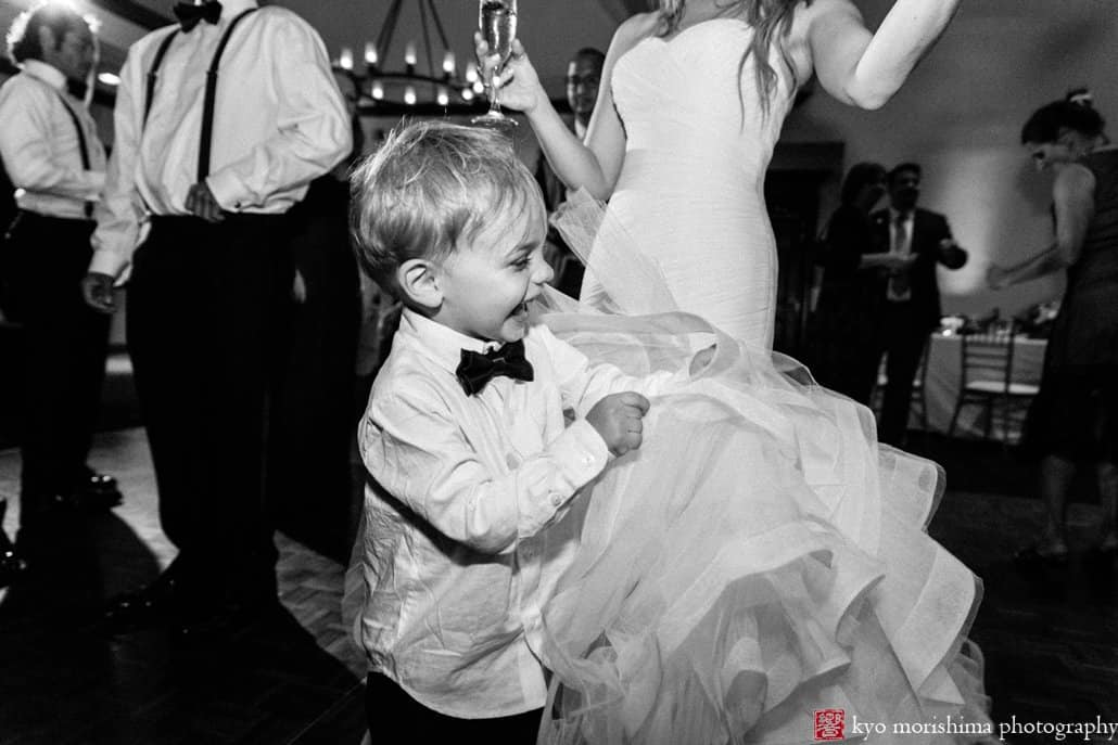 Ring bearer laughs as he grabs Pronovias wedding gown ruffles during Cherry Valley Country Club wedding reception