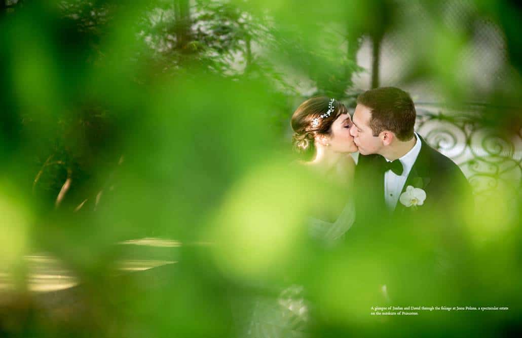 Jasna Polana wedding photo: bride and groom kiss on staircase near the tennis court, with greenery in the foreground