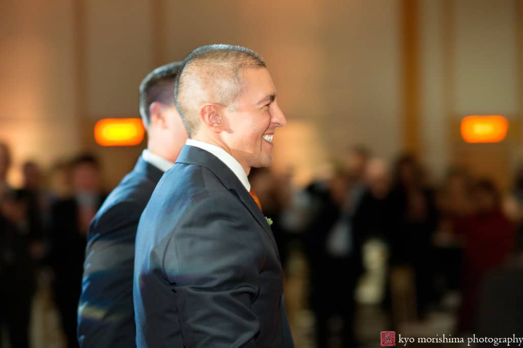 Grooms enter Hyatt Regency Princeton wedding reception and smile as guests cheer